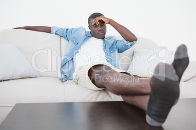 Casual man sitting on sofa with feet up