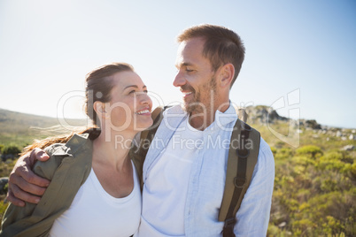 Hiking couple embracing and smiling on country terrain