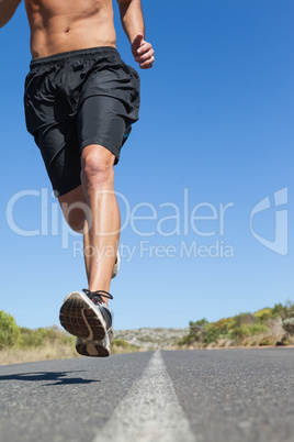 Shirtless man jogging on open road