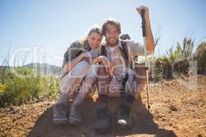 Hiking couple taking a break on mountain terrain smiling at came