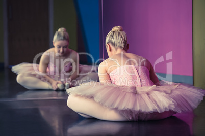 Graceful ballerina warming up in front of mirror