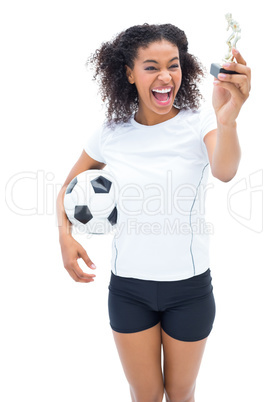 Pretty football player in white looking at winners figurine
