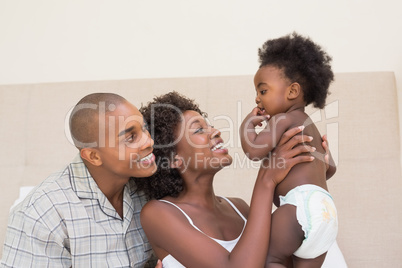 Happy couple on bed with baby daughter