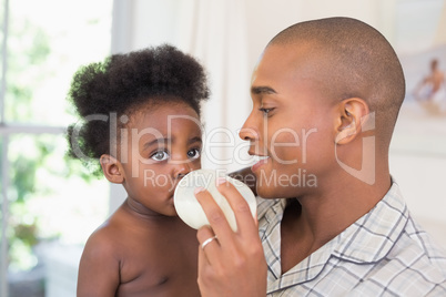 Happy father trying to feeding his baby girl