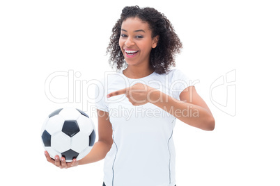 Pretty football fan in white holding ball and pointing to it