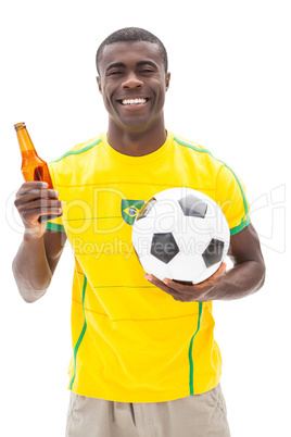 Happy brazilian football fan holding ball and beer