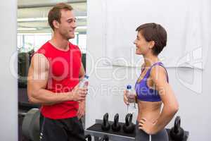 Fit attractive couple chatting holding water bottles