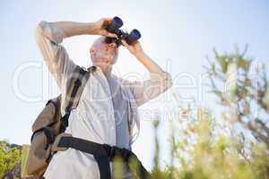 Hiker standing on country trail looking through binoculars