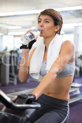 Fit woman taking a drink on the exercise bike