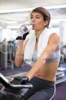Fit woman taking a drink on the exercise bike