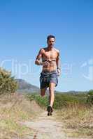 Shirtless man jogging with heart rate monitor around chest