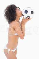 Athletic girl in white bikini kissing football