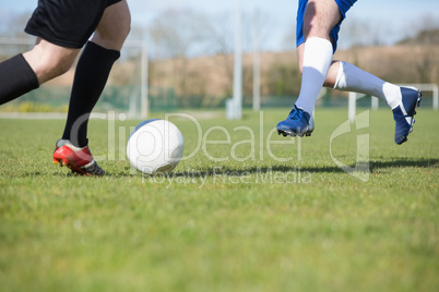 Football players tackling for the ball on pitch