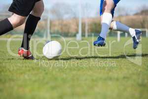 Football players tackling for the ball on pitch