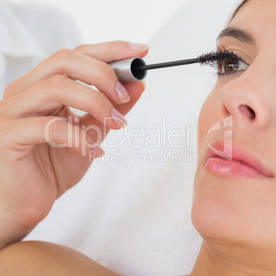 Hand applying mascara to beautiful woman