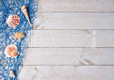 Shells and blue fishing net on wooden background