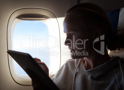 Woman sitting by illuminator in plane with touch pad