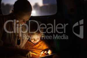 Mother and son with pad during car travel at night