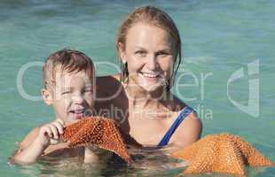 Mother and son in sea holding starfish