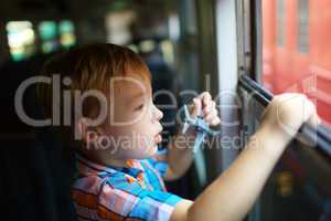 Little boy with toy looking out of train window