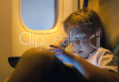 Little boy using tablet computer during flight