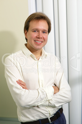 Happy young man with folded arms indoor