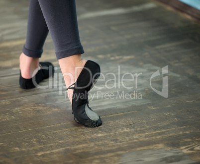 Close up view to ballerinas legs in pointes on wooden floor