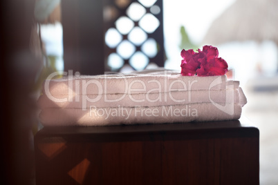 Pile of three white clean towels with flower on top