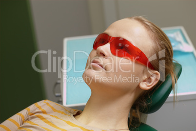 Woman in red safety glasses in dental office