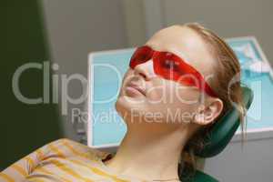 Woman in red safety glasses in dental office