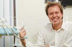 Laughing man with tousled hair holding dental tool