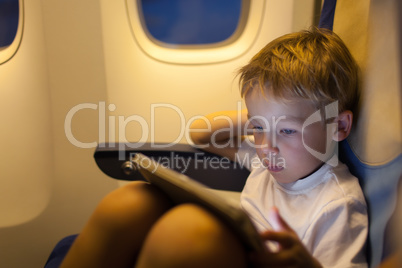 Boy sitting in the plane and using tablet PC