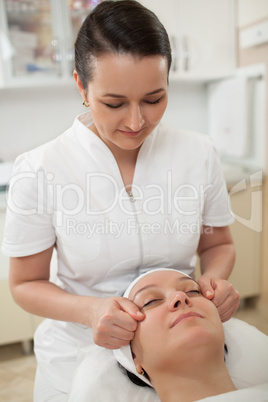 Woman under facial massage at beauty spa