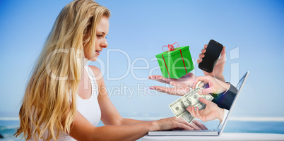 Composite image of pretty blonde using her laptop at the beach