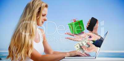 Composite image of pretty blonde using her laptop at the beach