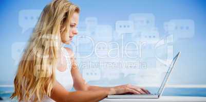 Composite image of pretty blonde using her laptop at the beach