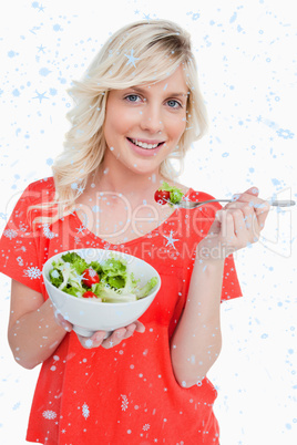 Composite image of young smiling woman eating a fresh salad with