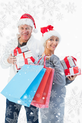 Composite image of festive mature couple in winter clothes holdi