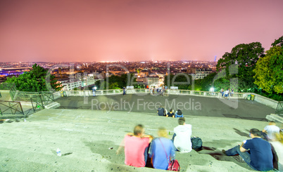 Tourists in Montmartre steps enjoying Paris night skyline