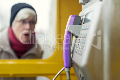 Staunende Seniorin an einer Telefonzelle