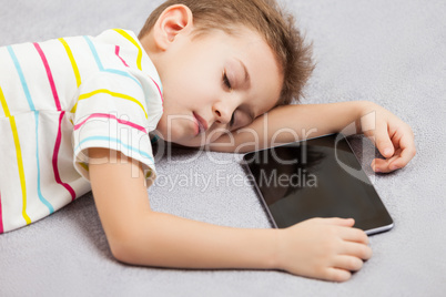 Tired sleeping child boy holding tablet computer