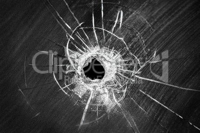 Bullet shot cracked hole on broken window glass