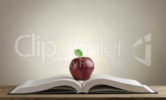 open book on a wooden Desk with a red Apple