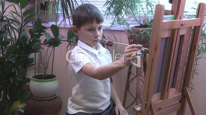 boy draws a picture on the easel