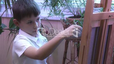 boy draws a picture on the easel