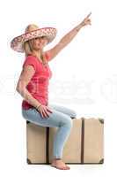 Eine Frau sitzt auf einem Koffer und zeigt nach oben