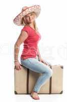 Frau mit Sombrero sitzt auf einem Koffer