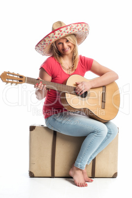 Frau sitzt auf einem Koffer und spielt Gitarre