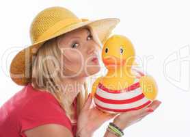 Blonde Frau mit Strohhut küsst eine Badeente