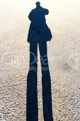 Elongated Shadow of a Person Standing on the Road